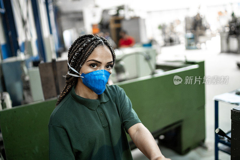 图为一位中年妇女在工厂/工业中工作，戴着防护口罩